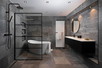 Moderne badkamer met vrijstaand bad, inloopdouche met glazen wand, dubbele wastafel met spiegel, en zwarte badkamermeubels. Luxe ontwerp met grijze tegels en ingebouwde verlichting.