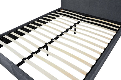 Close-up van een grijs gestoffeerd bedframe met lattenbodem, zonder matras, geplaatst op een witte achtergrond.