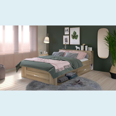 Houten tweepersoonsbed met groene en roze dekens en kussens, ingebouwde opberglades, geplaatst in een gezellige slaapkamer met groene muren, raam en decoratieve elementen.