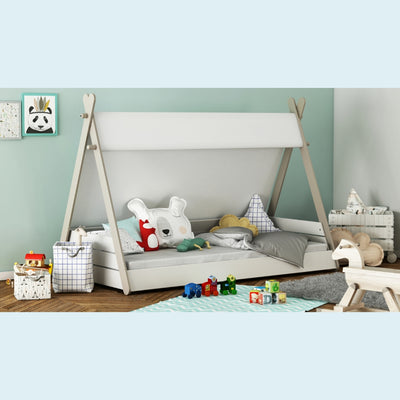Kinderbed in de vorm van een tent met witte en grijze beddengoed en decoratieve kussens, geplaatst in een kinderkamer met houten vloer en speelgoed.