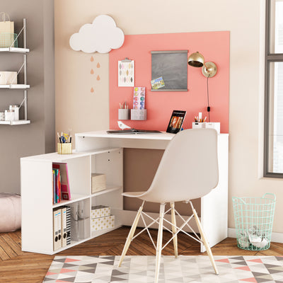 Moderne thuiswerkplek met wit hoekbureau en open opbergvakken, ingericht met een laptop, decoraties, en een grijze stoel. Geel bureaulamp en kleurrijke wanddecoratie voor een inspirerende werkruimte.
